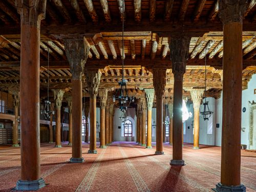 Free Interior view of a historic mosque featuring ornate wooden columns and chandeliers. Stock Photo