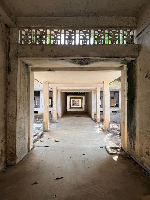 Free A perspective view of an abandoned concrete corridor in a dilapidated building, showcasing decay. Stock Photo