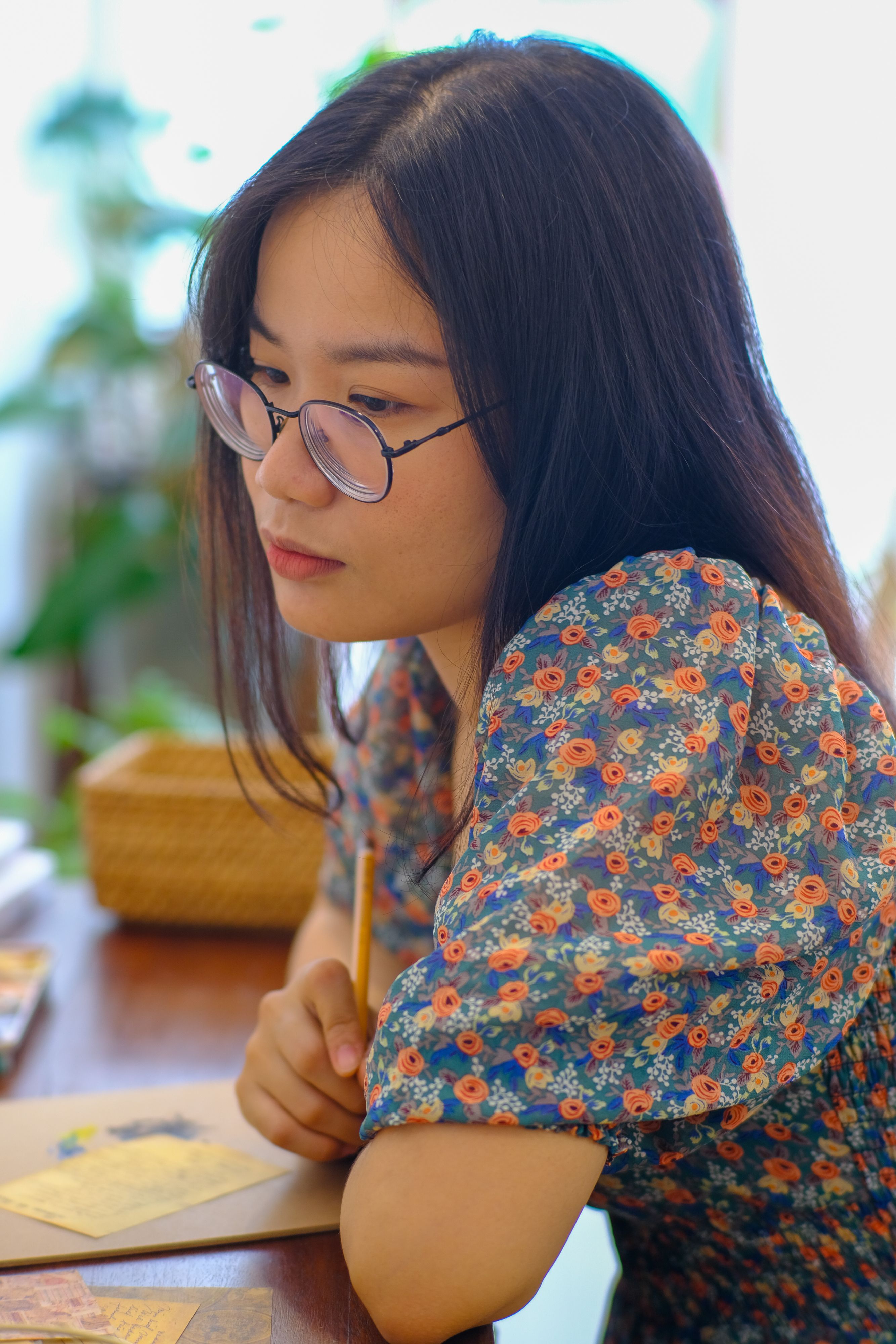 A young woman in Hue, Vietnam, pens a letter in a calm, indoor setting.