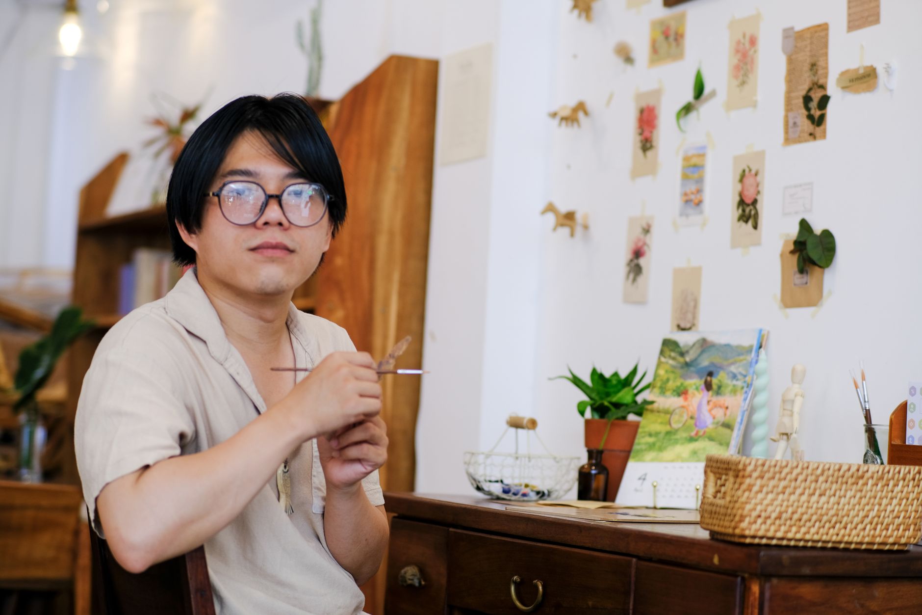 A creative portrait of a man with glasses in an artistic workspace in Hue, Vietnam.