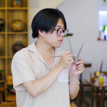 Portrait of an artisan focused on delicate crafting in a workshop in Hue, Vietnam.