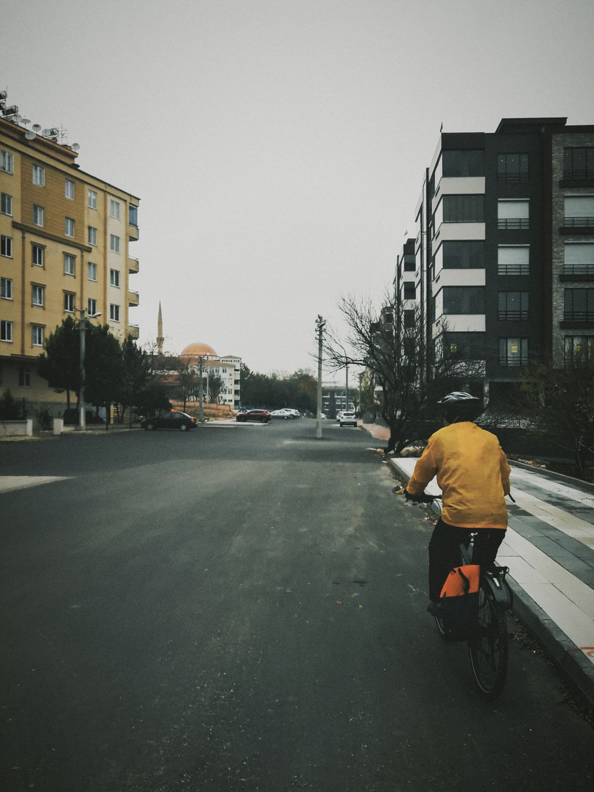 Cyclist in a bright jacket riding through a modern urban street