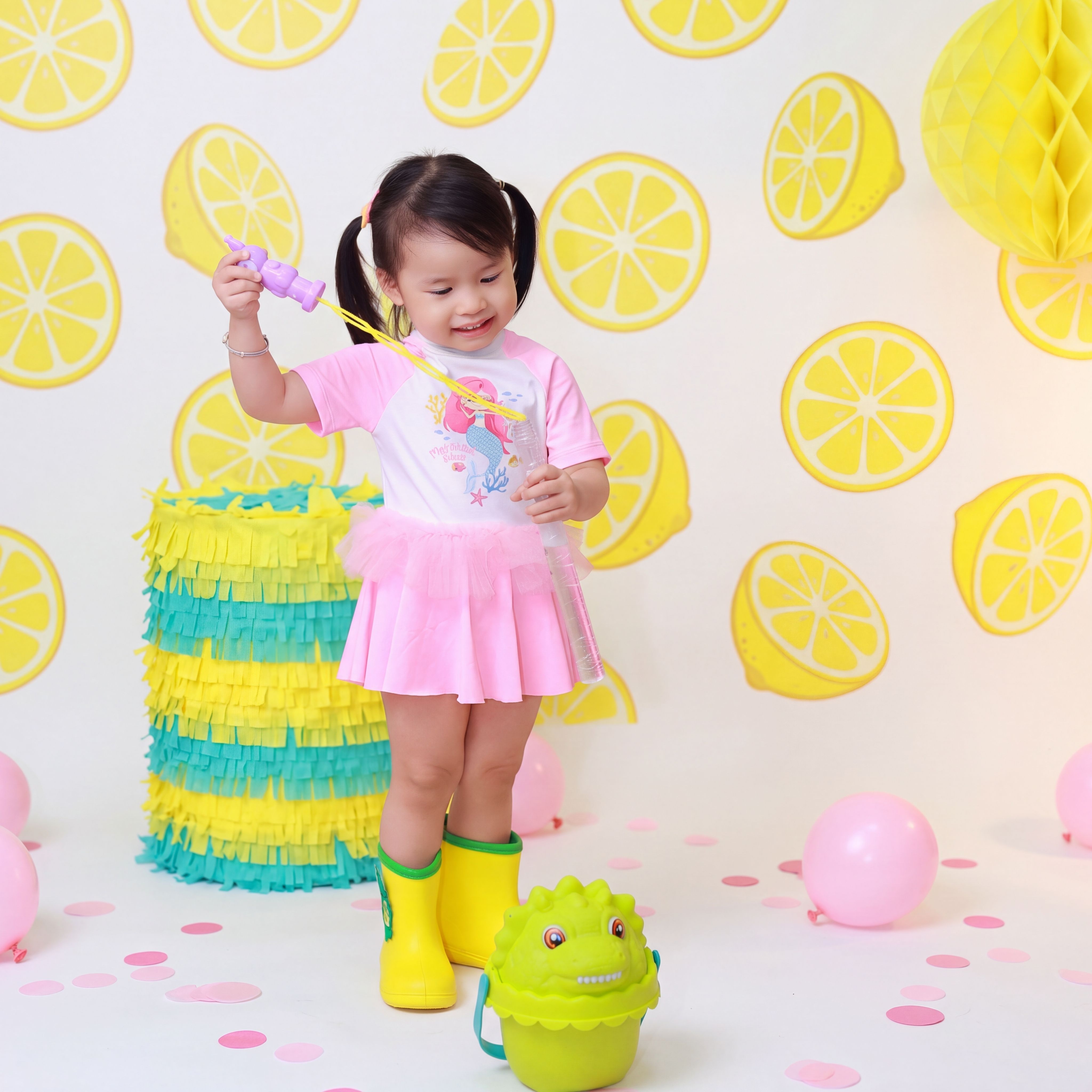 Smiling child playing with bubbles at a vibrant lemon-themed party.