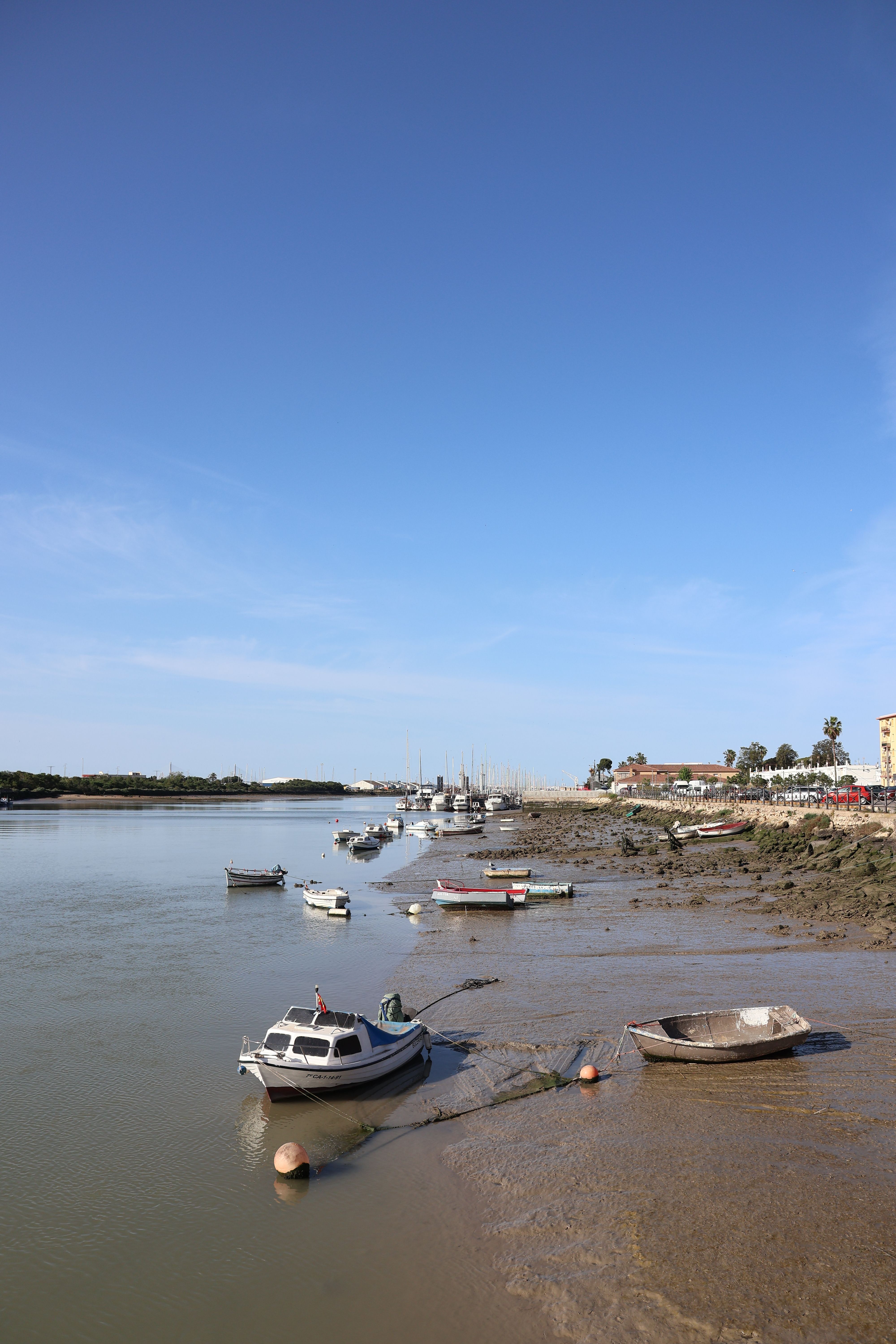 Scenic view of boats moored at low tide along the riverbank in El Puerto de Santa María, Spain.