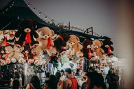 狂欢节现场晚上热闹非凡，有泰迪熊奖品和熙攘的人群