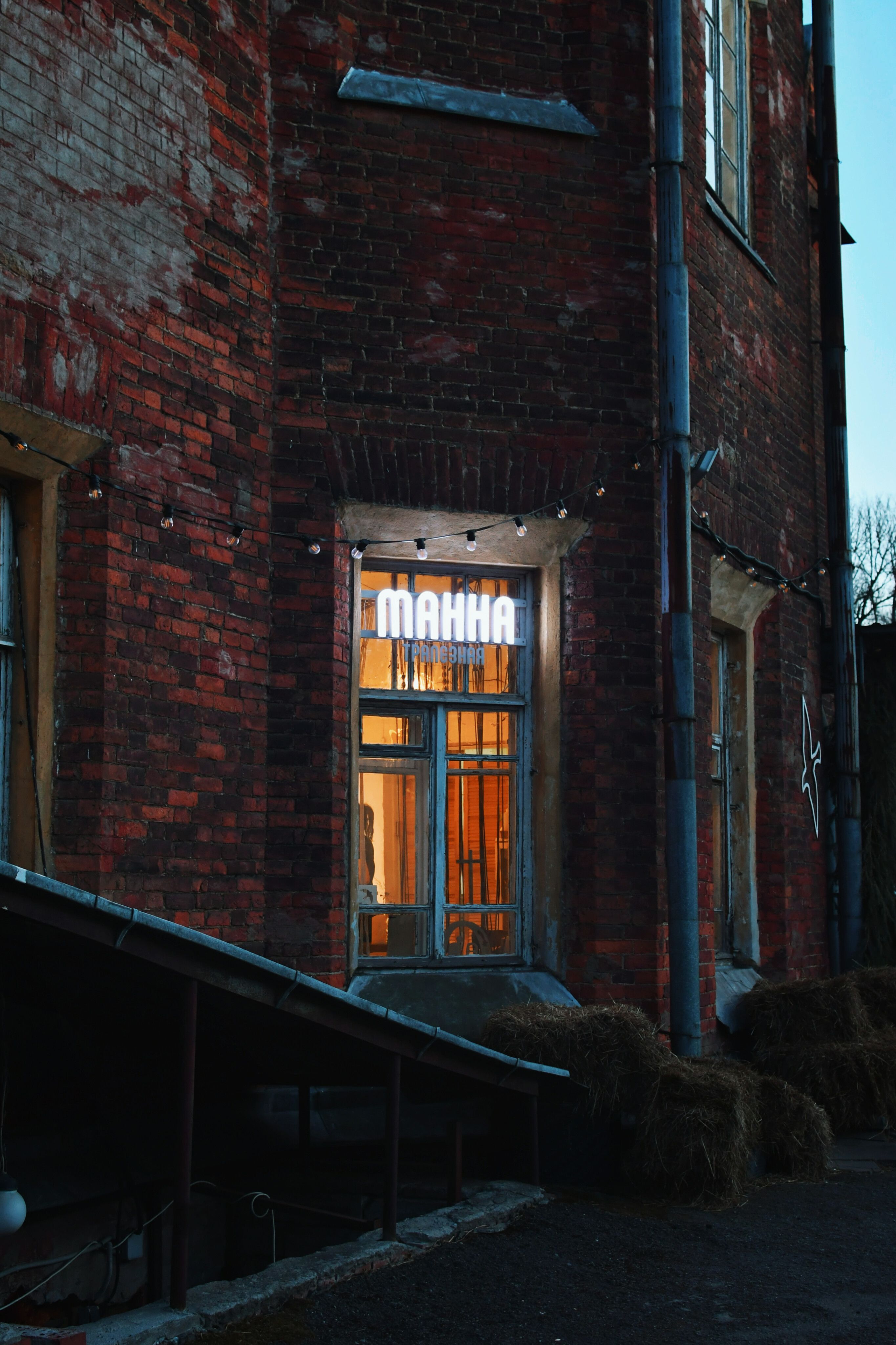 Cozy warm glow from a historic brick building window with an illuminated sign at twilight.