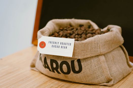 Sack of freshly roasted cacao beans with label 'Freshly Roasted Cacao Bean', ideal for coffee and chocolate themes.