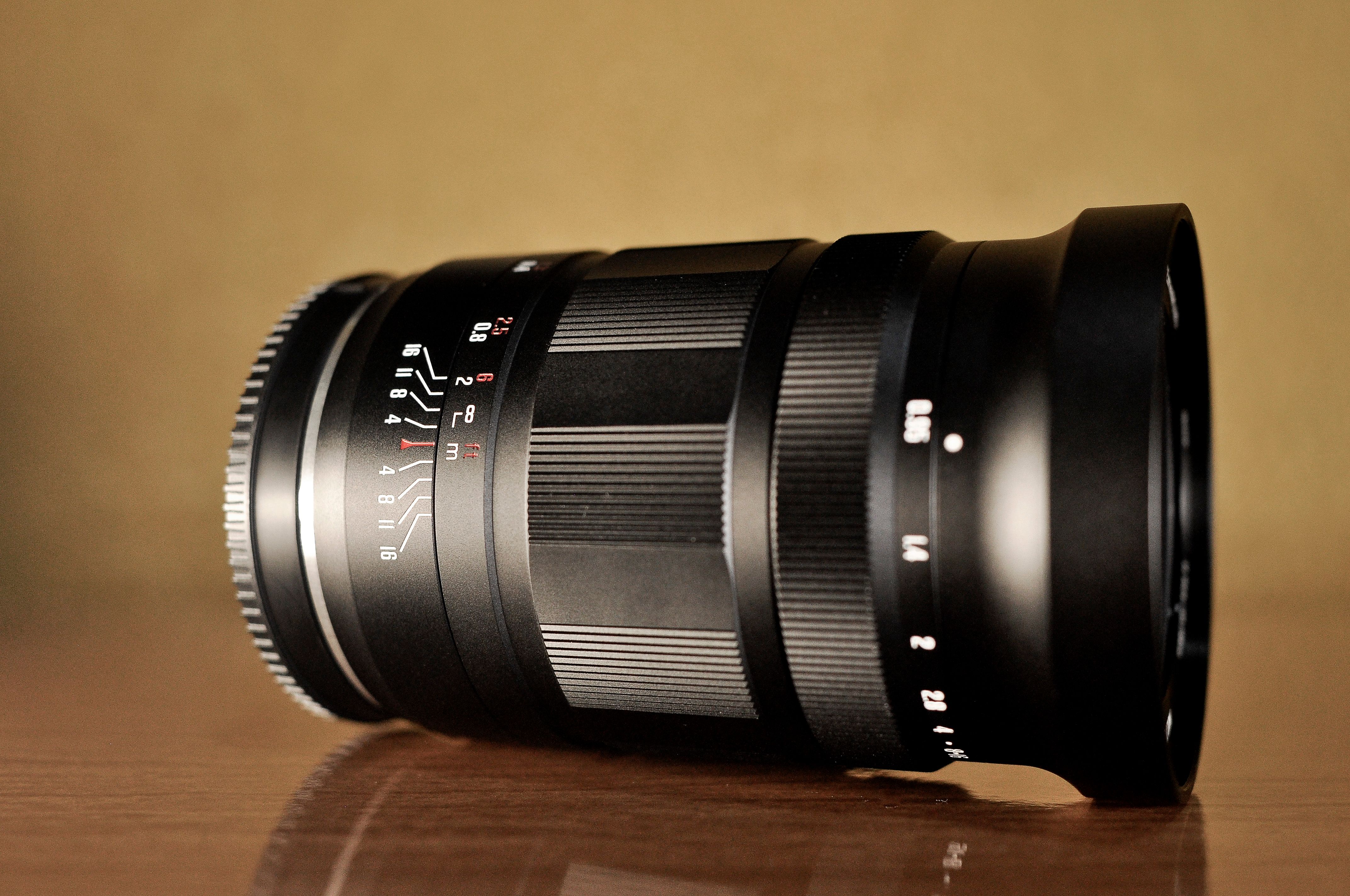 Detailed shot of a black camera lens placed on a wooden table, perfect for photography enthusiasts.
