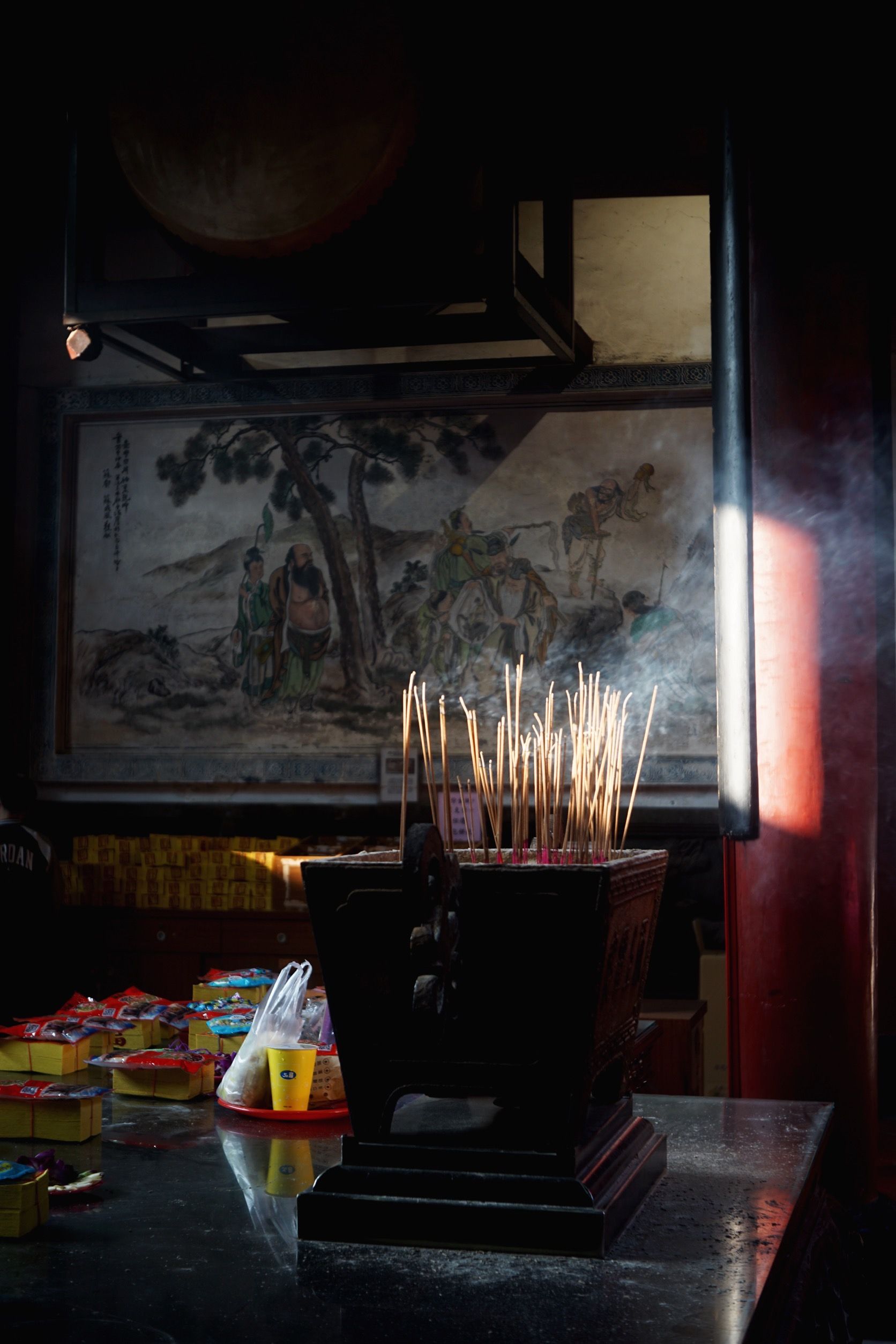Interior view of a Taiwanese temple hall with burning incense and carved decoration