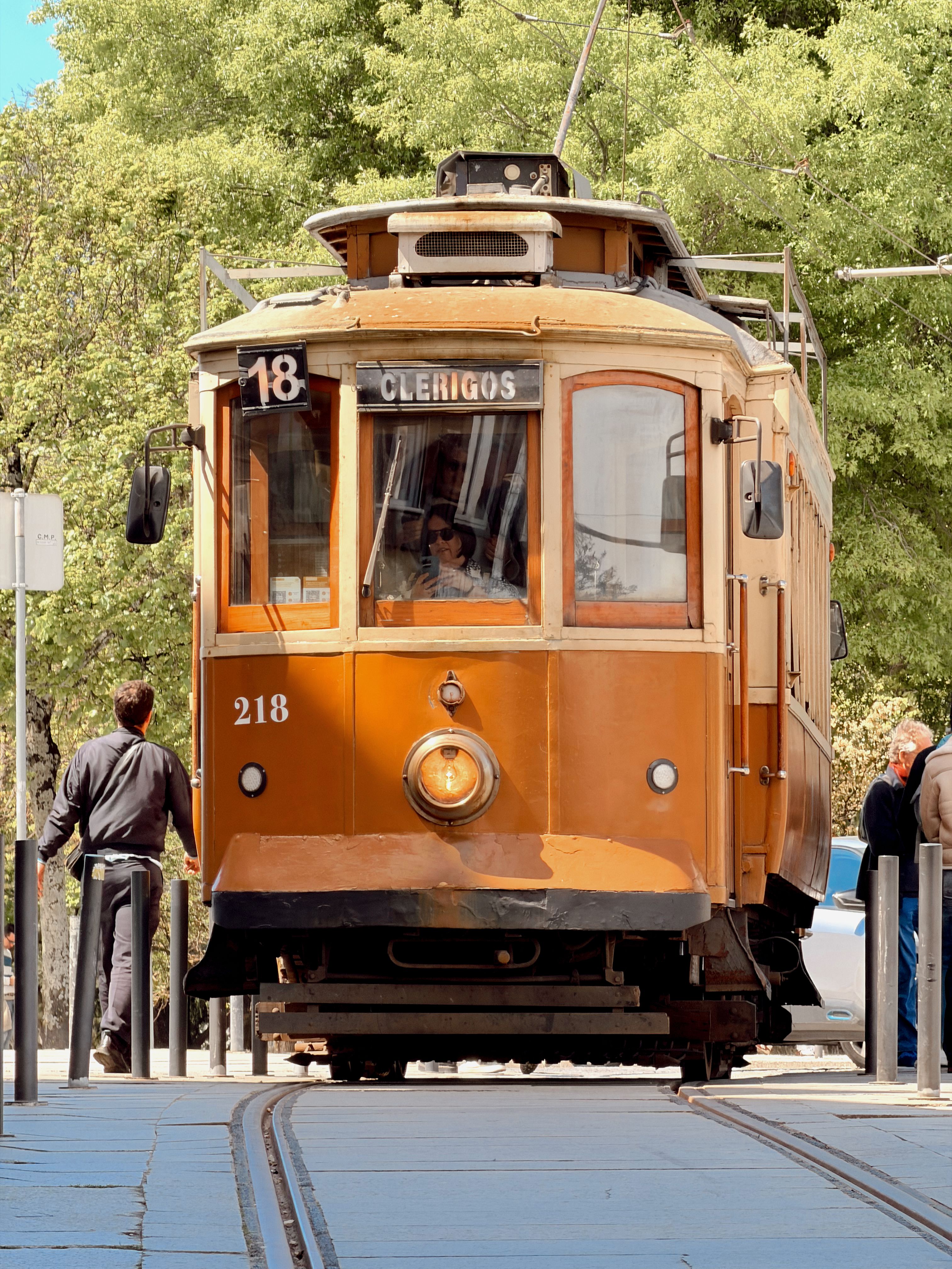 Vintage tram number 18 traversing the streets of Porto, Portugal under sunny skies.