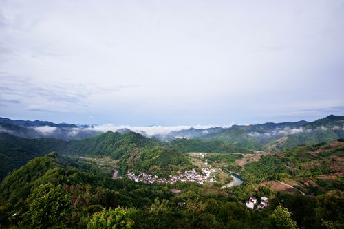 Free Aerial view of a picturesque village nestled in verdant mountains under a clear sky. Stock Photo
