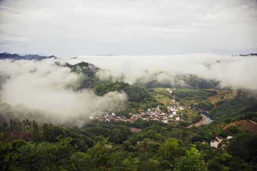 Free A picturesque mountain village surrounded by lush greenery and clouds, creating a serene and tranquil scene. Stock Photo