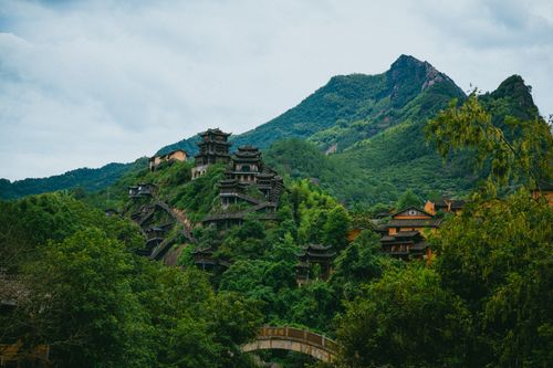 Free Picturesque view of traditional Chinese architecture nestled in lush green mountains, vibrant and serene. Stock Photo