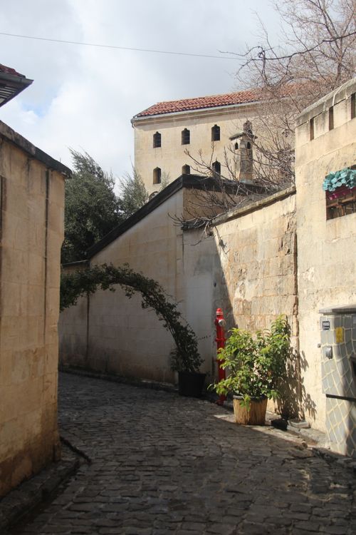 Free Explore a quaint cobblestone alleyway lined with historic stone buildings under a cloudy sky. Stock Photo