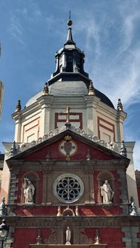 Close-up of the ornate architectural detail of a historic Spanish church in Madrid, featuring statues and a domed roof.