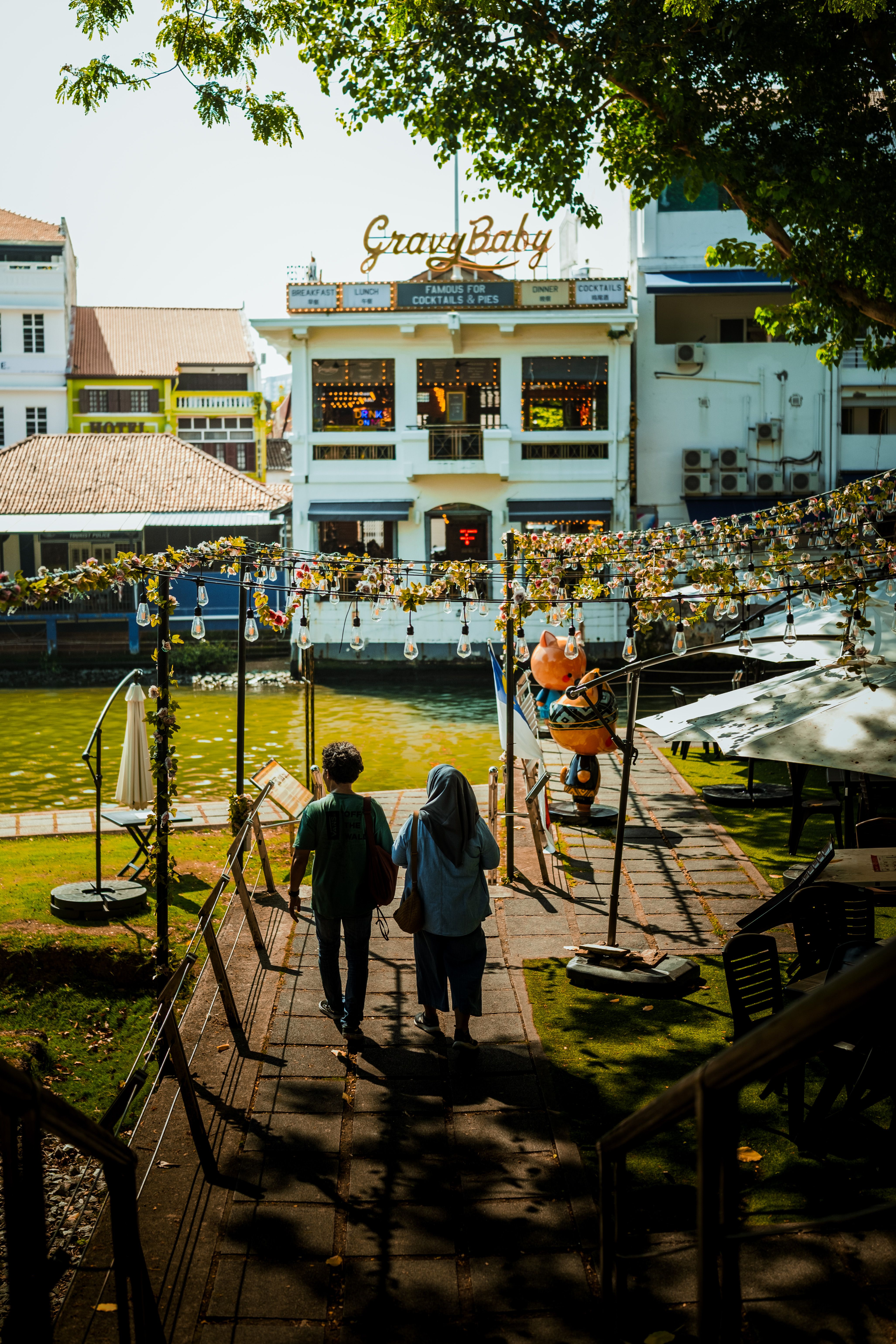 Gratuit Un couple profite d'une promenade tranquille le long des rives pittoresques du fleuve dans la ville historique de Malacca, en Malaisie. Photos