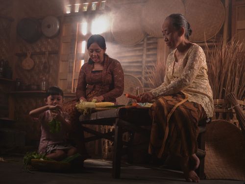 Free A family engages in traditional cooking in a warm, rustic Indonesian kitchen setting. Stock Photo