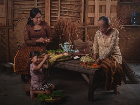 A family preparing traditional Indonesian dishes in a rustic village setting. - Fotografer Sidoarjo