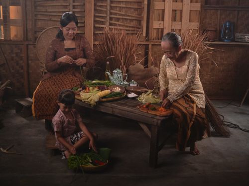 Free An Indonesian family prepares traditional dishes together in a rustic setting. Stock Photo
