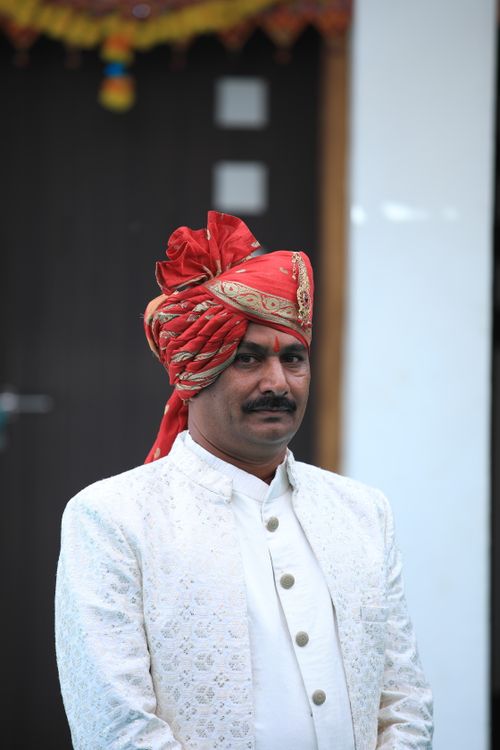 Free A portrait of a groom in traditional Indian attire featuring an ornate turban and white sherwani. Stock Photo