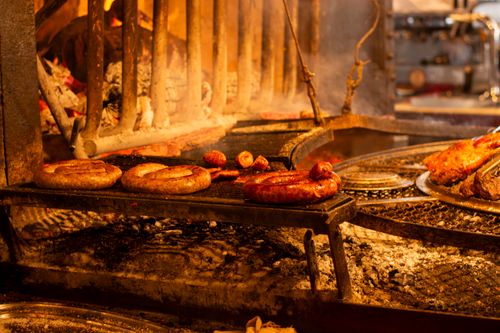 Free Grilled sausages and meats on an open fire grill, creating a rustic and appetizing scene. Stock Photo