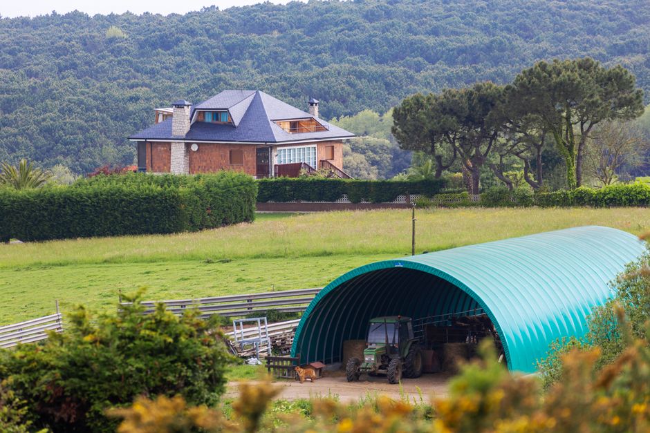 Idílica casa de campo con un moderno invernadero y exuberante vegetación.
