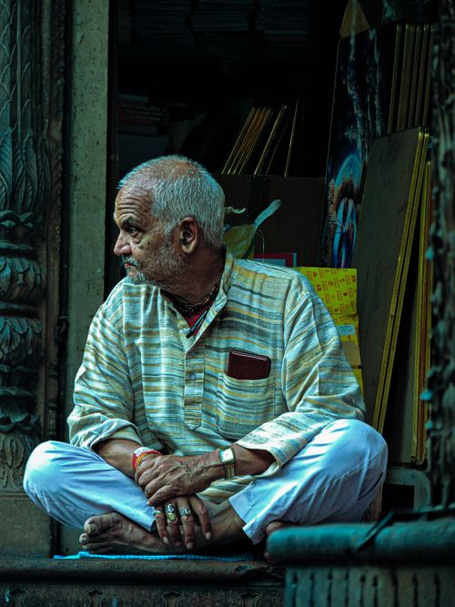 Free Portrait of a senior man sitting in a shop entrance, showcasing traditional Indian attire. Stock Photo