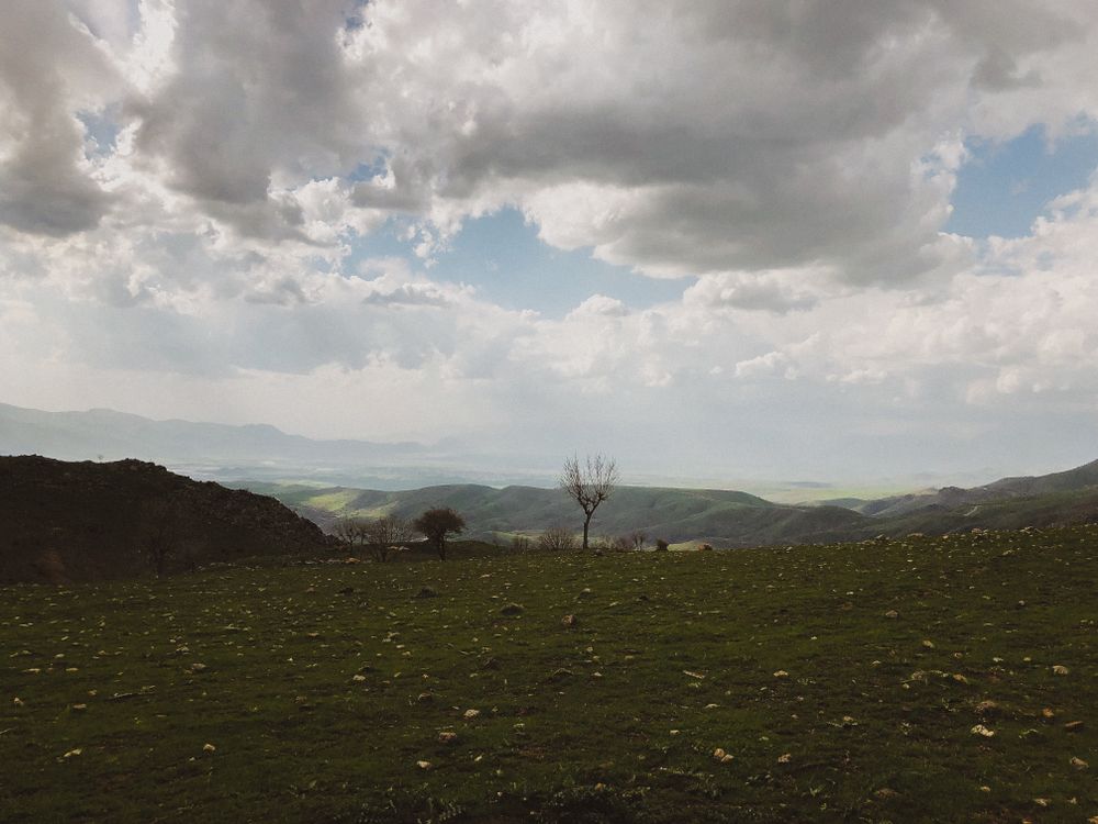 Free Scenic view of rolling hills and dramatic clouds over a lush green countryside. Stock Photo