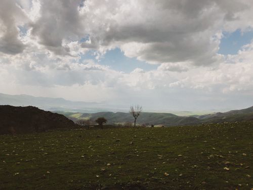 Free Scenic view of rolling hills and dramatic clouds over a lush green countryside. Stock Photo