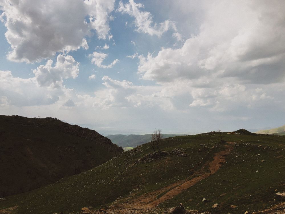 Free A breathtaking view of mountainous terrain under a sky filled with dramatic clouds. Stock Photo