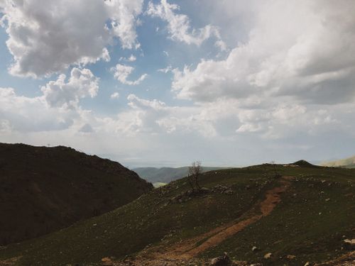 Free A breathtaking view of mountainous terrain under a sky filled with dramatic clouds. Stock Photo
