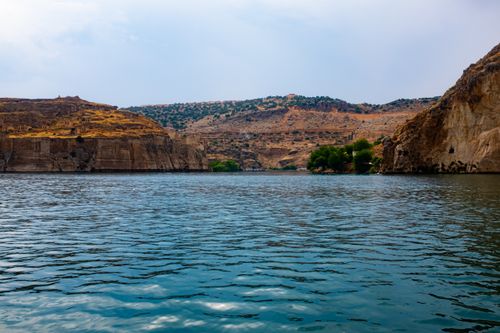 Free Peaceful riverscape with rocky cliffs and lush greenery under a summer sky. Stock Photo
