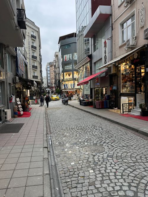 Free A bustling street with cobblestone path lined with shops and a lively urban setting. Stock Photo