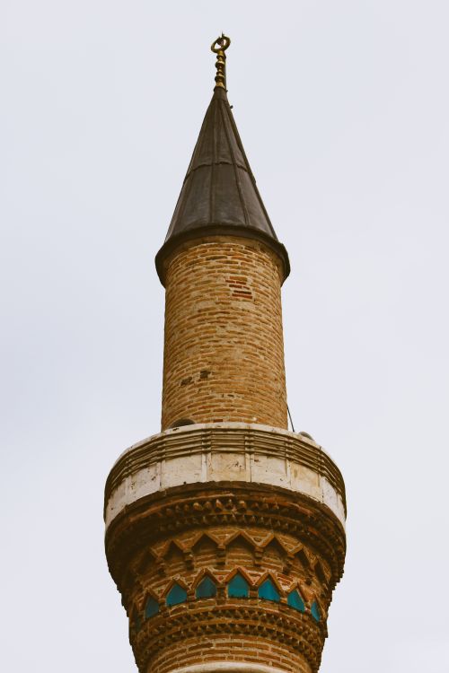 Free A close-up of a historic brick minaret featuring decorative details against a clear sky. Stock Photo