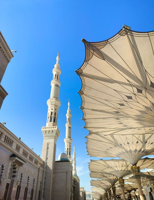 Free View of Al-Masjid an-Nabawi showing its iconic towers and umbrellas against a clear sky in Madinah, Saudi Arabia. Stock Photo