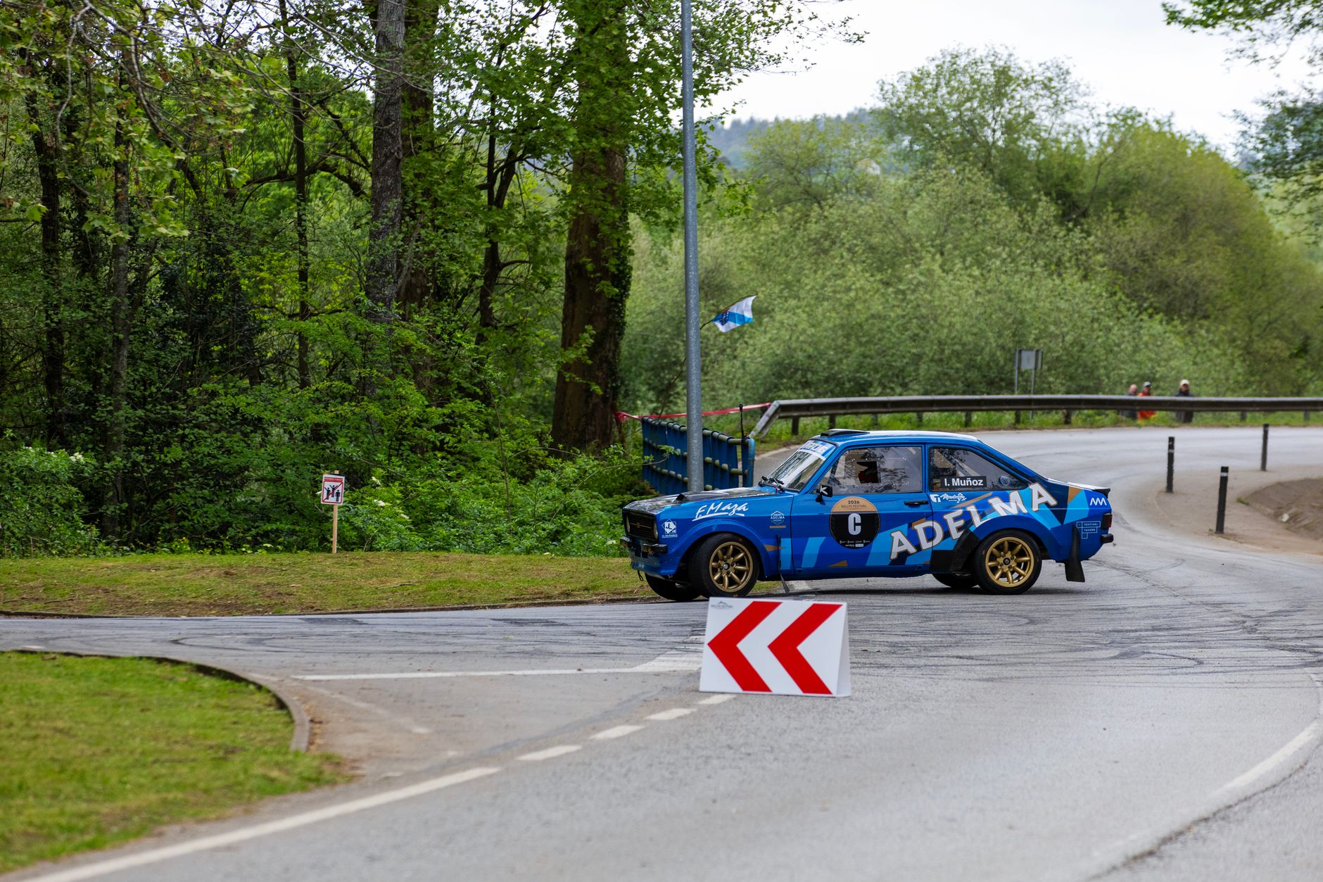 Blue vintage rally car taking a sharp turn on a forest road