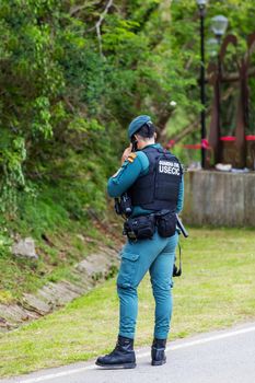 Guardia Civil officer in uniform standing outdoors, communicating via radio.