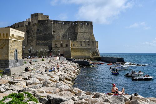 Free A vibrant scene of Castel dell'Ovo and its bustling seaside, capturing boats and beachgoers in Naples, Italy. Stock Photo