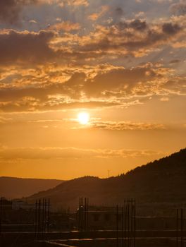 A breathtaking view of the sun setting over hills, creating a warm and dramatic sky.
