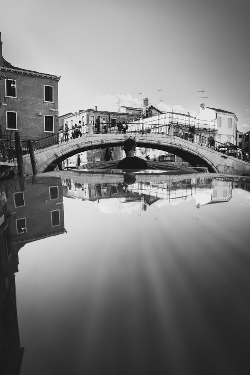 Free Artistic black and white photo of a Venetian canal with bridge reflection, capturing urban serenity. Stock Photo