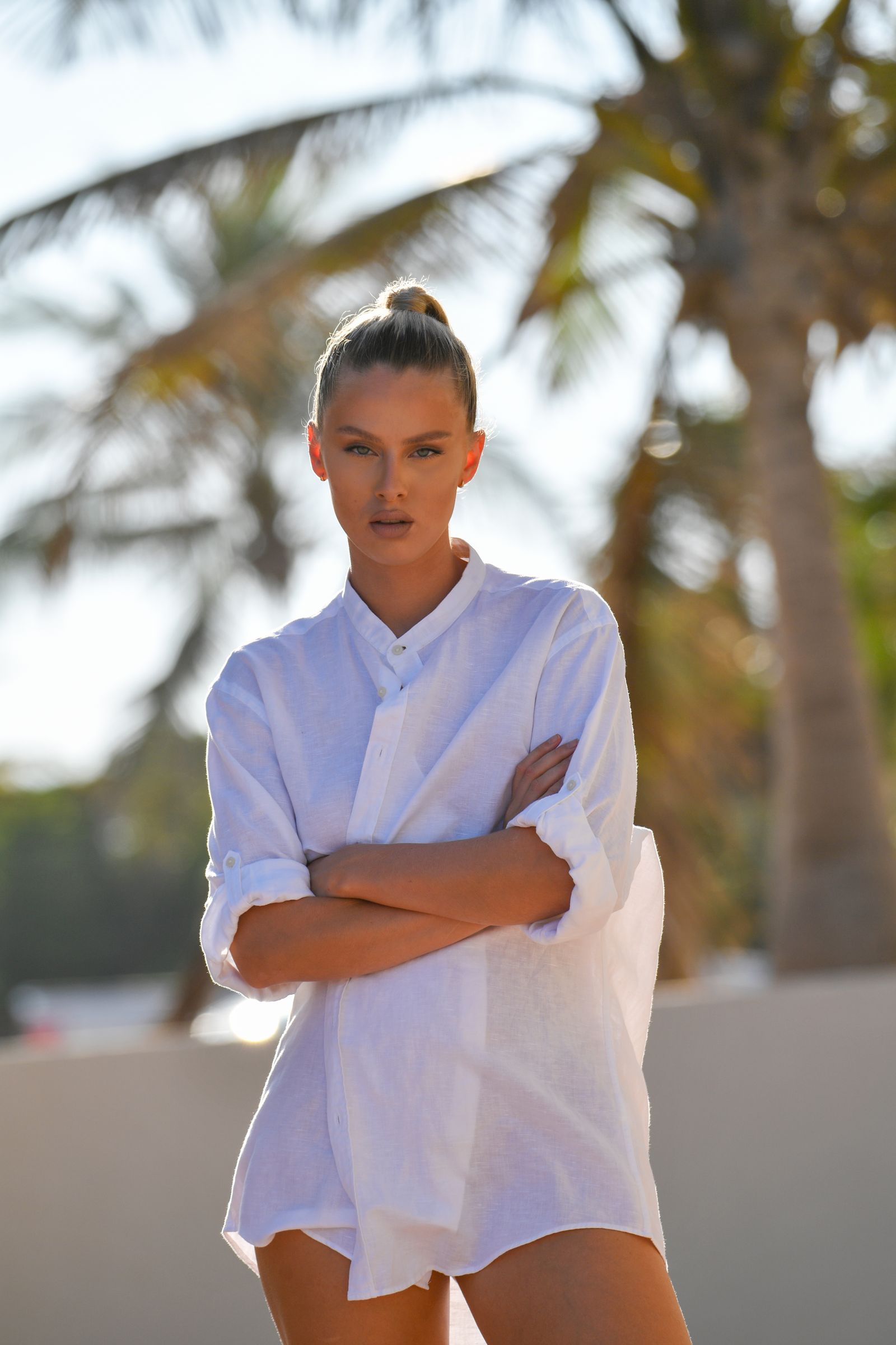 Woman wearing sophisticated white linen resortwear at a tropical beach resort