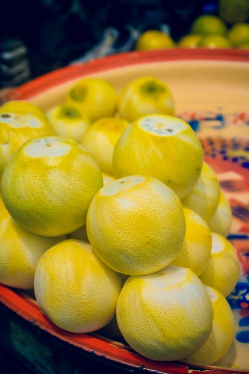 Free Stack of ripe yellow lemons displayed in a colorful Nigerian market. Stock Photo