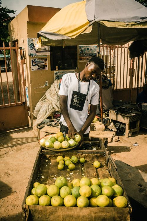 Free Young man selling fresh oranges at a local market in Nigeria, illustrating everyday life. Stock Photo