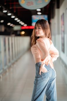 一位身着休闲装的年轻女子面带微笑，在柔和的灯光下于室内摆出姿势，氛围温暖