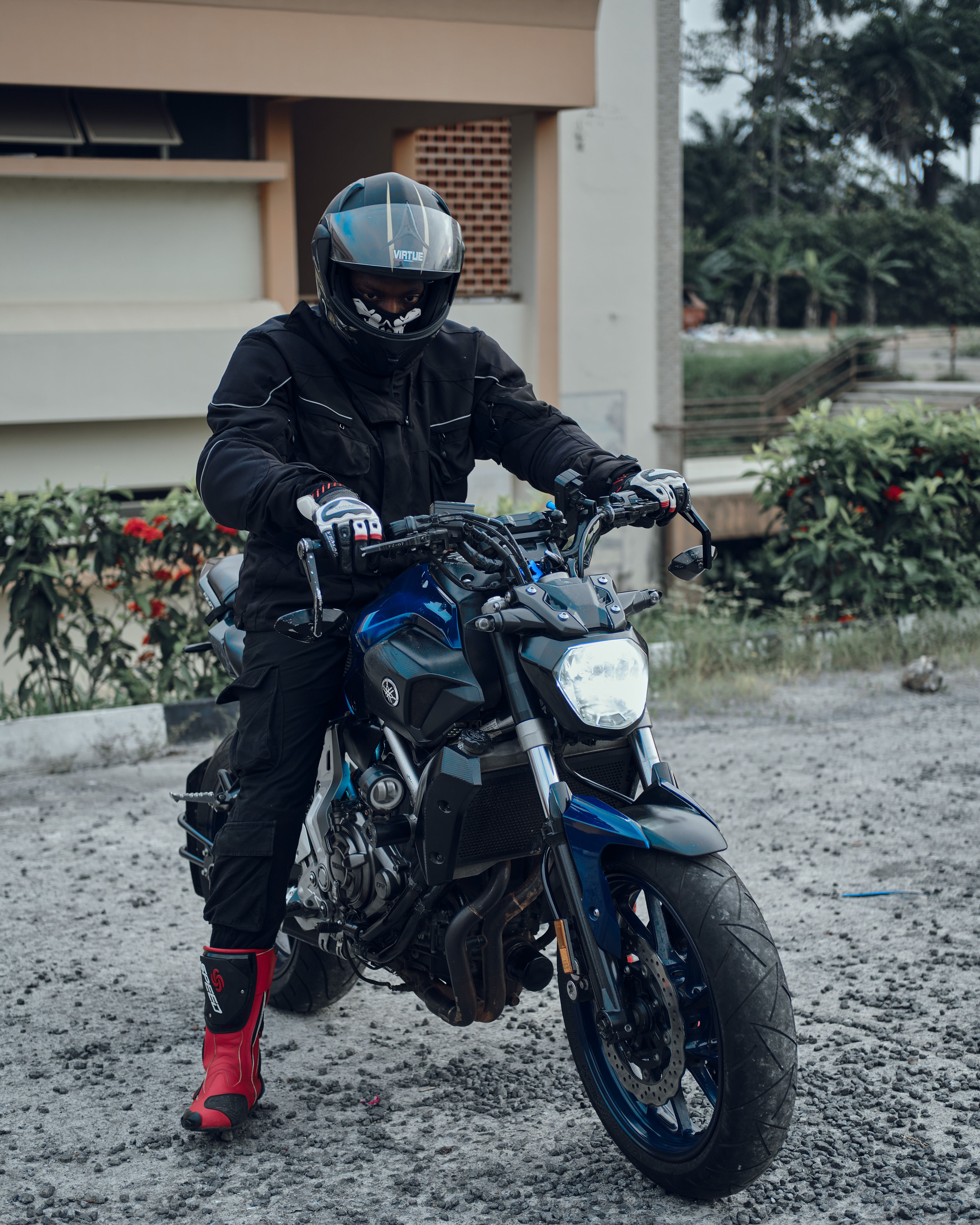 Motorcyclist wearing protective gear on a street with greenery.