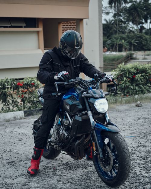 Free Man in black gear poses with blue motorcycle outdoors during the day. Stock Photo