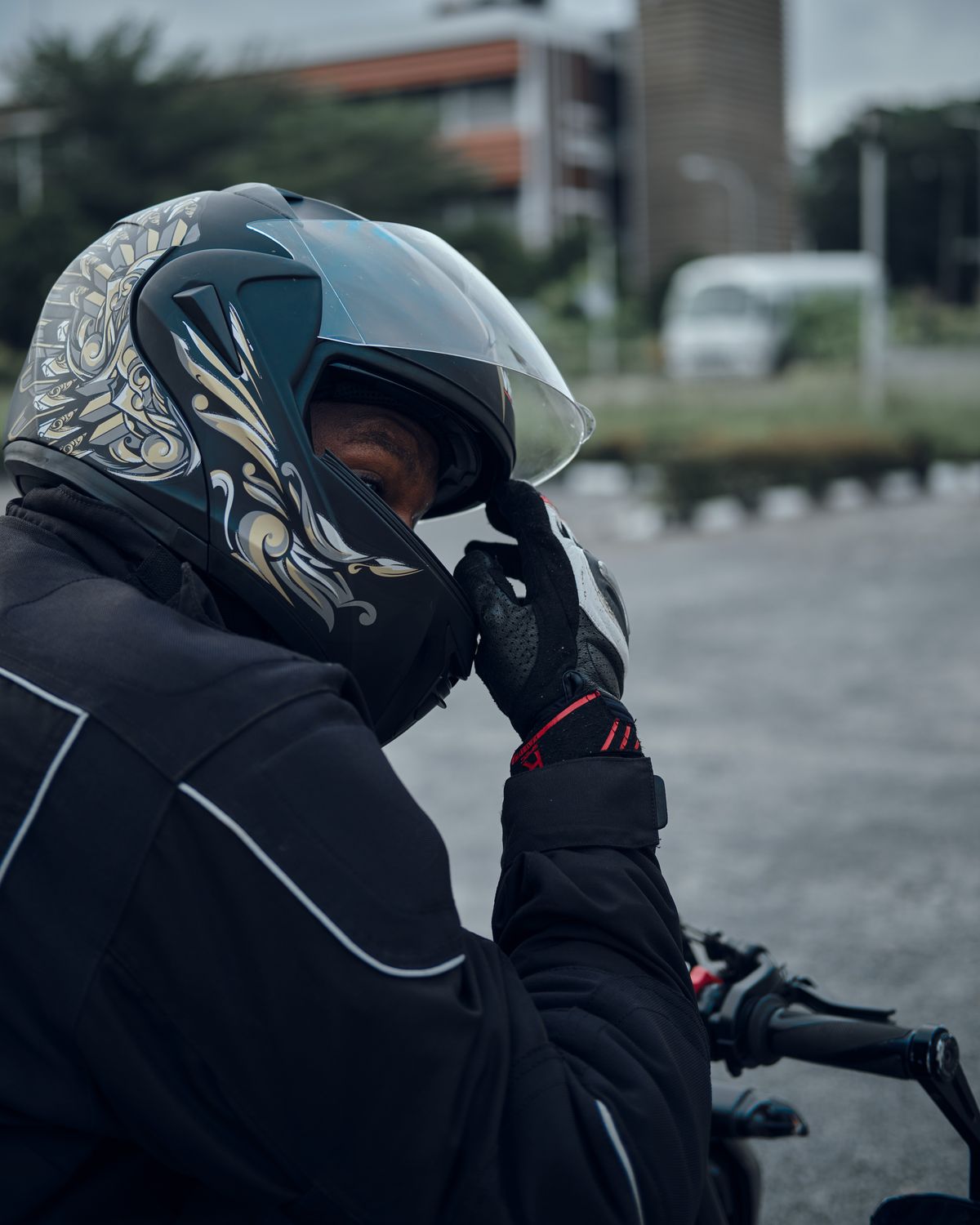 Motorcyclist Adjusting Helmet in Urban Setting · Free Stock Photo