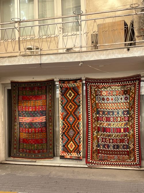 Free Vibrant traditional rugs displayed on a street wall, showcasing intricate patterns. Stock Photo