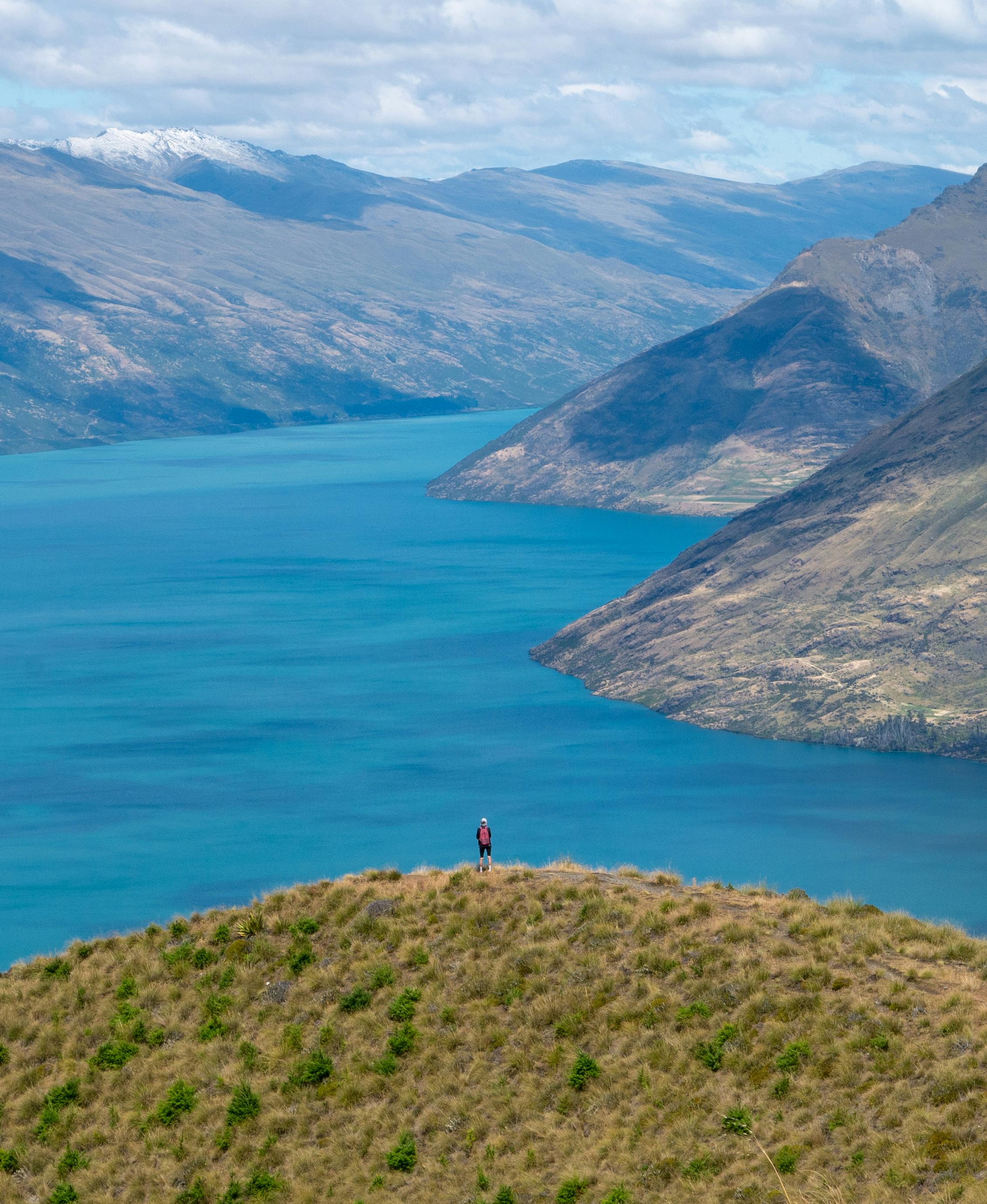 A lone traveler admires the breathtaking view of a mountain lake vista.