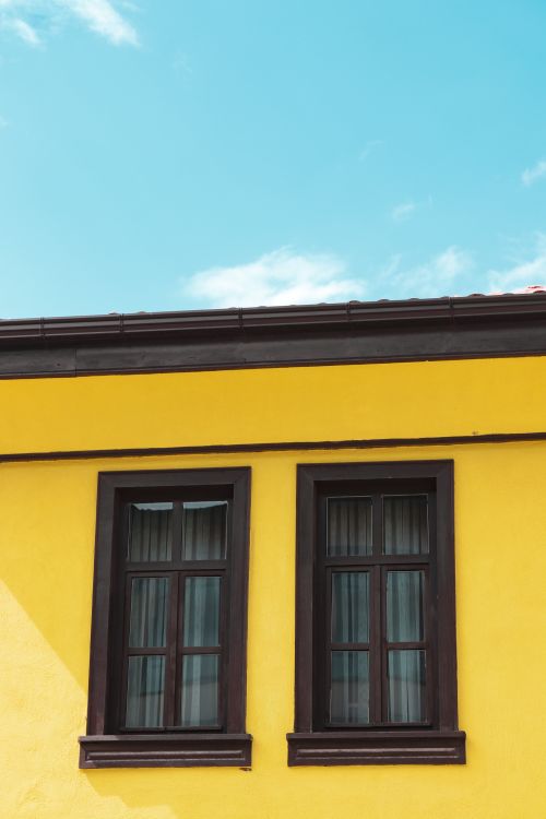 Free Colorful yellow building facade with dual windows under a clear sky in Eskişehir, Türkiye. Stock Photo